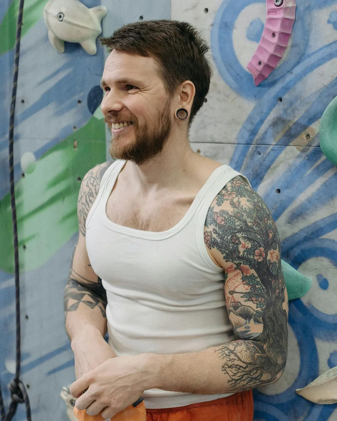 Rock climber wearing white under shirt and orange shorts
