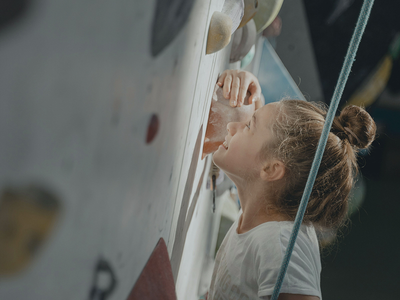 Young climber looking up a holds