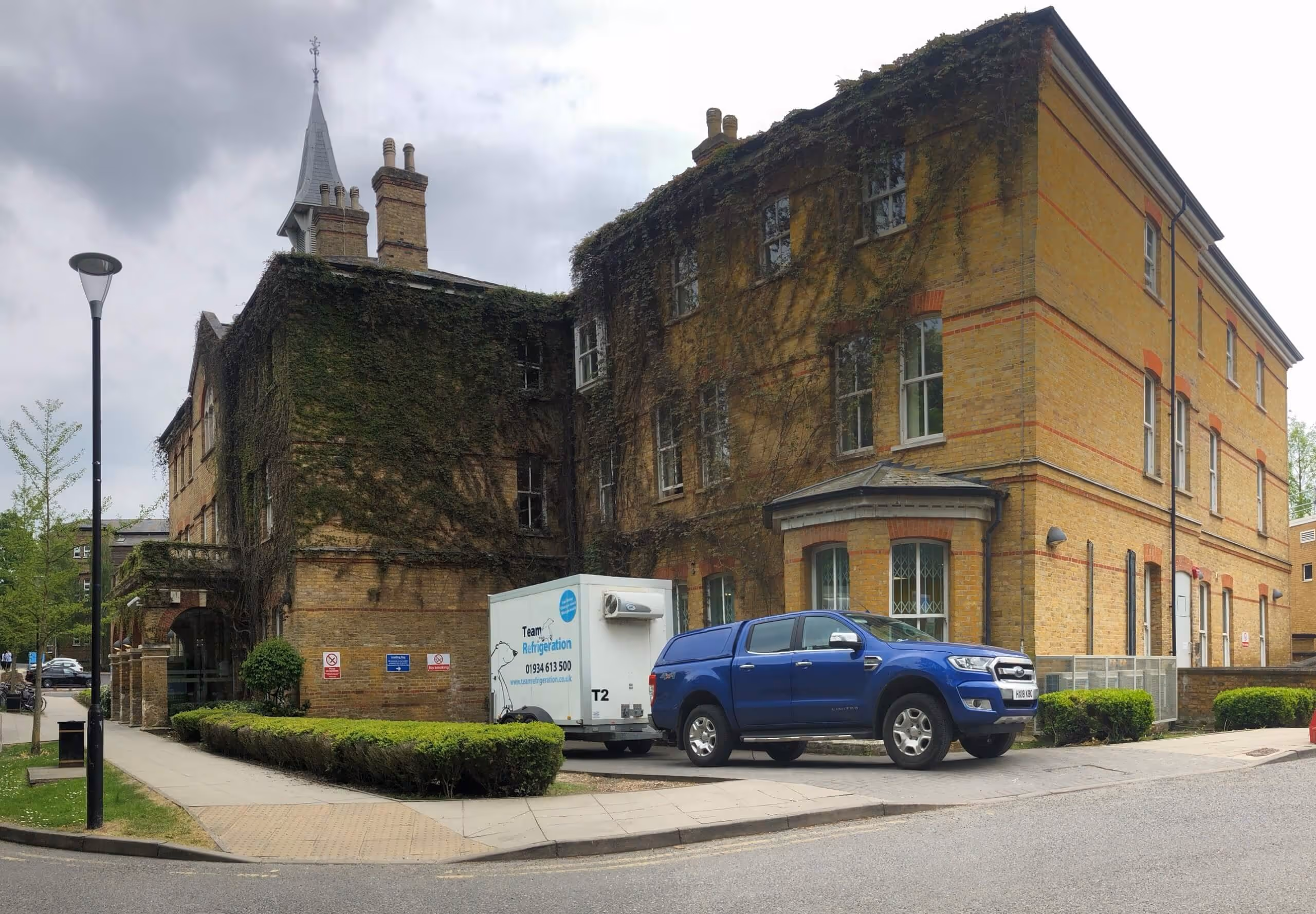 A blue truck parked in front of a large building.