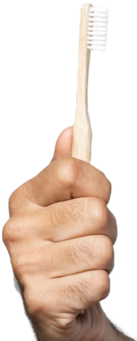 Hand holding a bamboo toothbrush with white bristles against a white background.