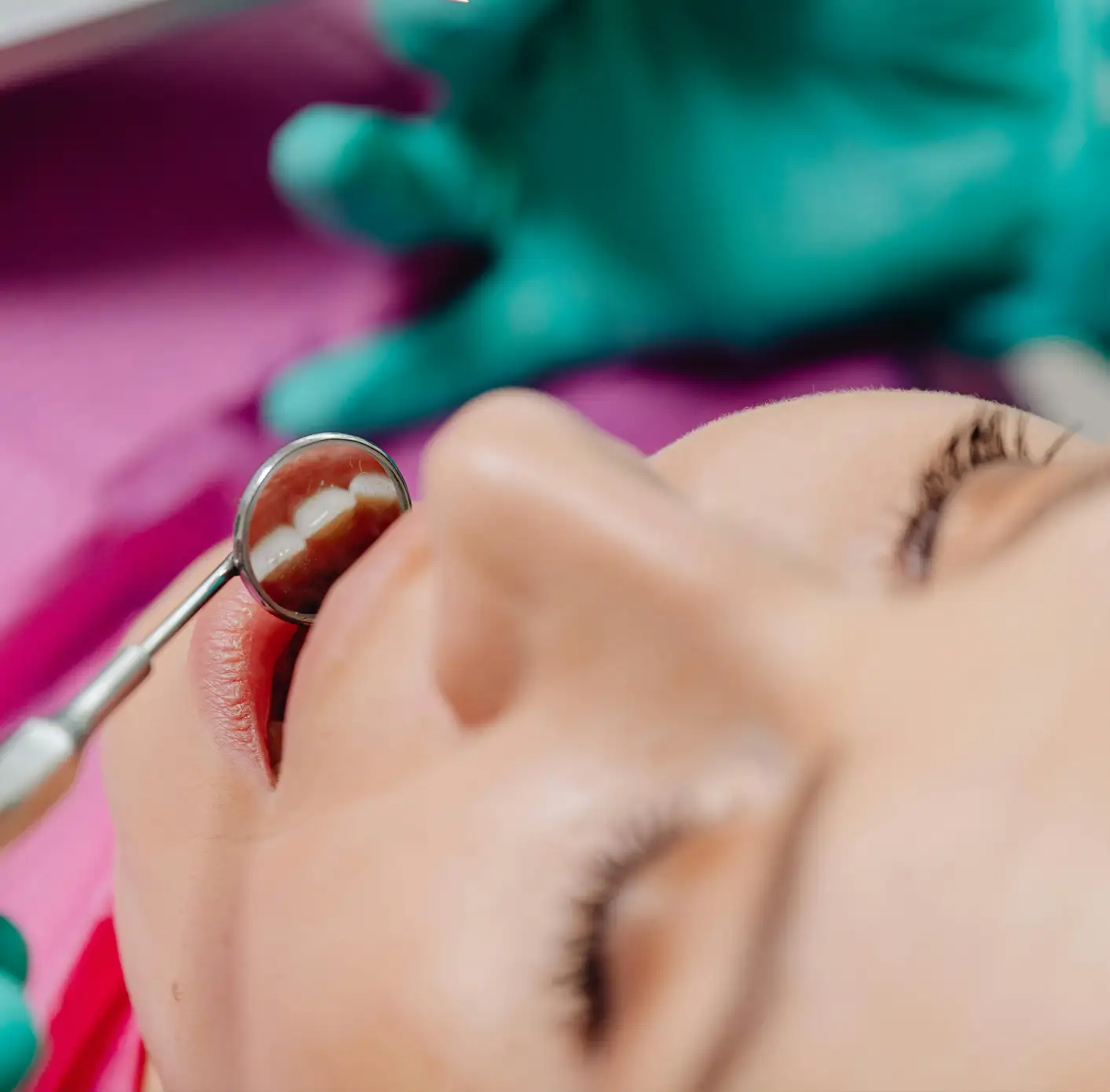 Close-up of a dental mirror reflecting teeth inside a patient's open mouth during a dental checkup.