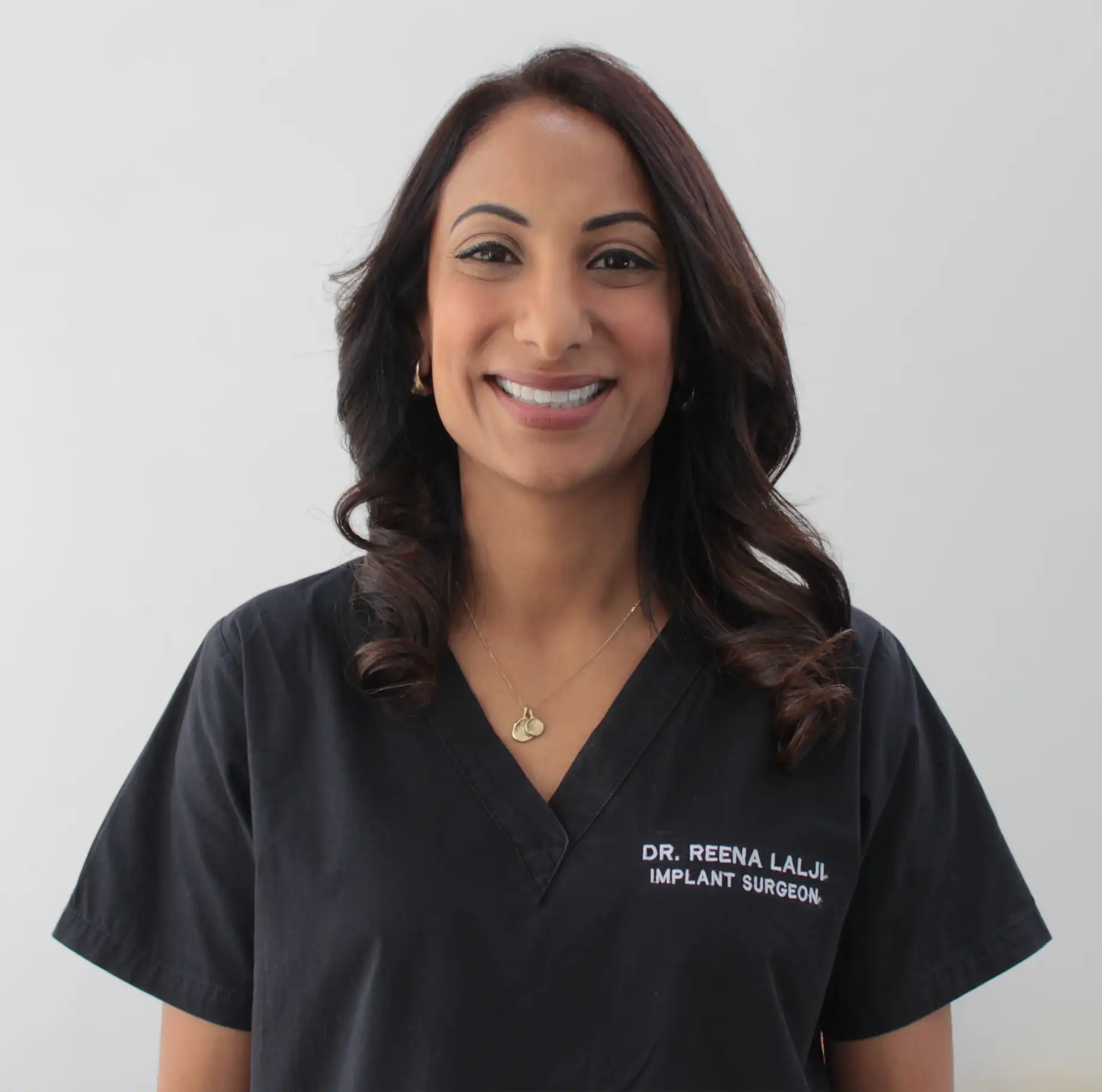 Dr Reena standing, smiling at the camera.