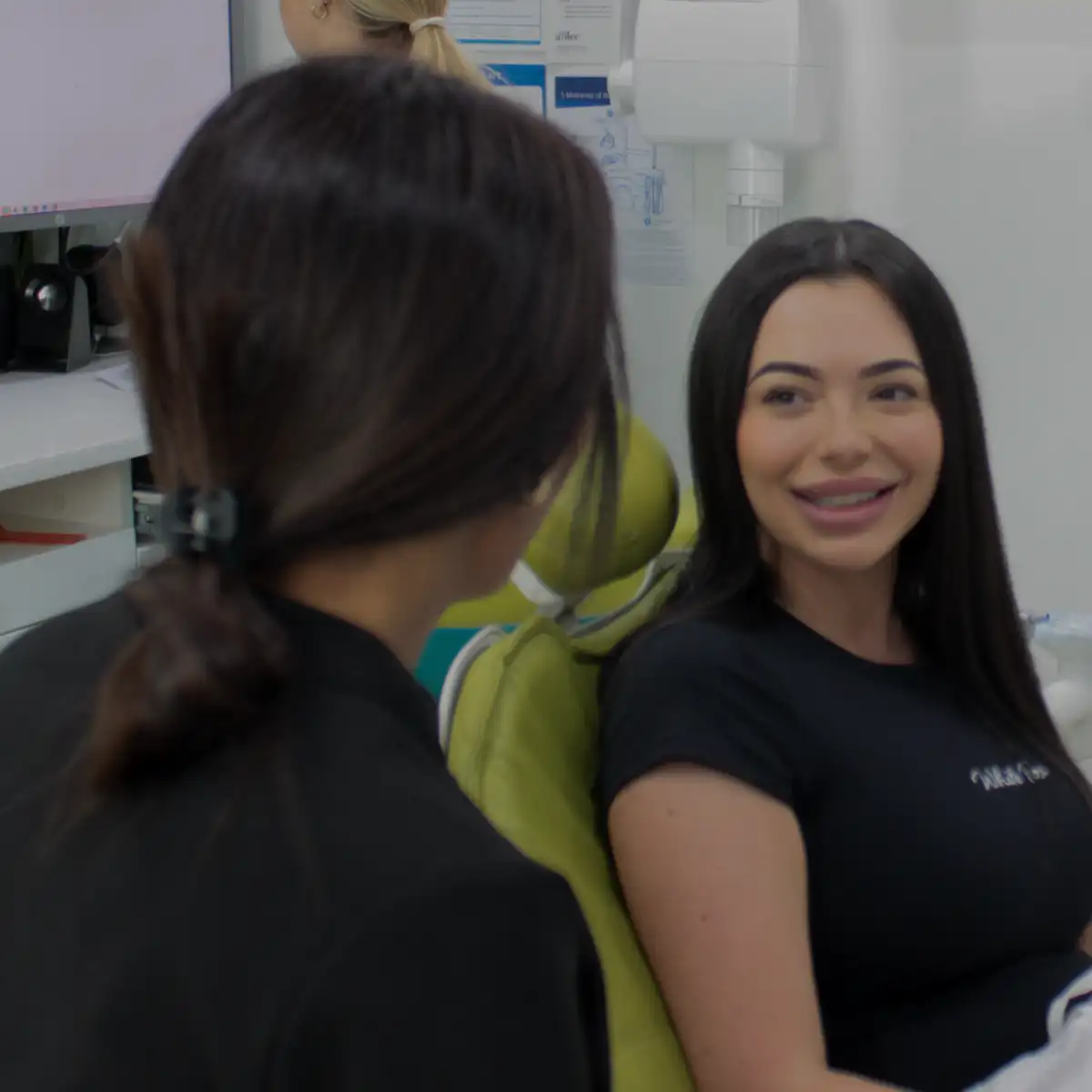 Smiling woman sitting in a dental chair talking to a dental professional.