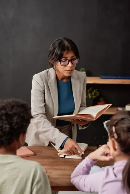 un enseignant lisant un livre et expliquant quelque chose à 2 enfants