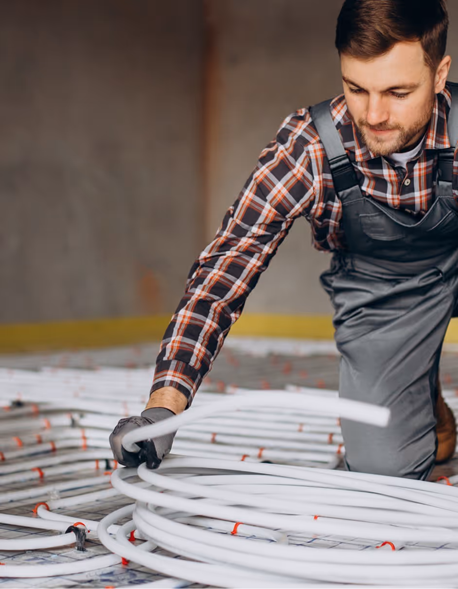 Ein Mann, der Leitungen für Fussbodenheizung verlegt