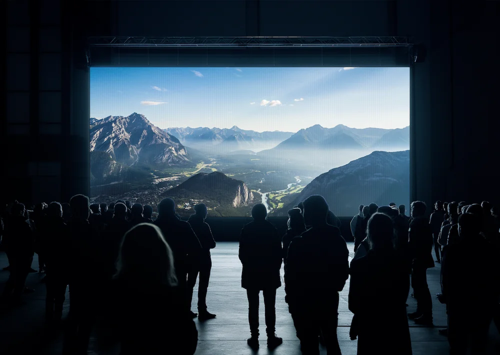 An audience watching a mountain landscape on a large cinema screen
