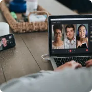 Person participating in a video call on a laptop showing three people's faces on screen.