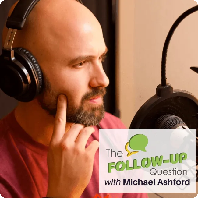 Bald man with a beard wearing headphones speaking into a microphone in a recording studio with text overlay 'The Follow-Up Question with Michael Ashford'.