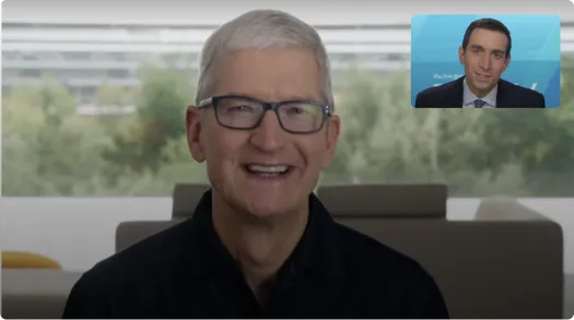 Smiling man with gray hair and glasses in dark shirt with a small inset of a man in a suit speaking.