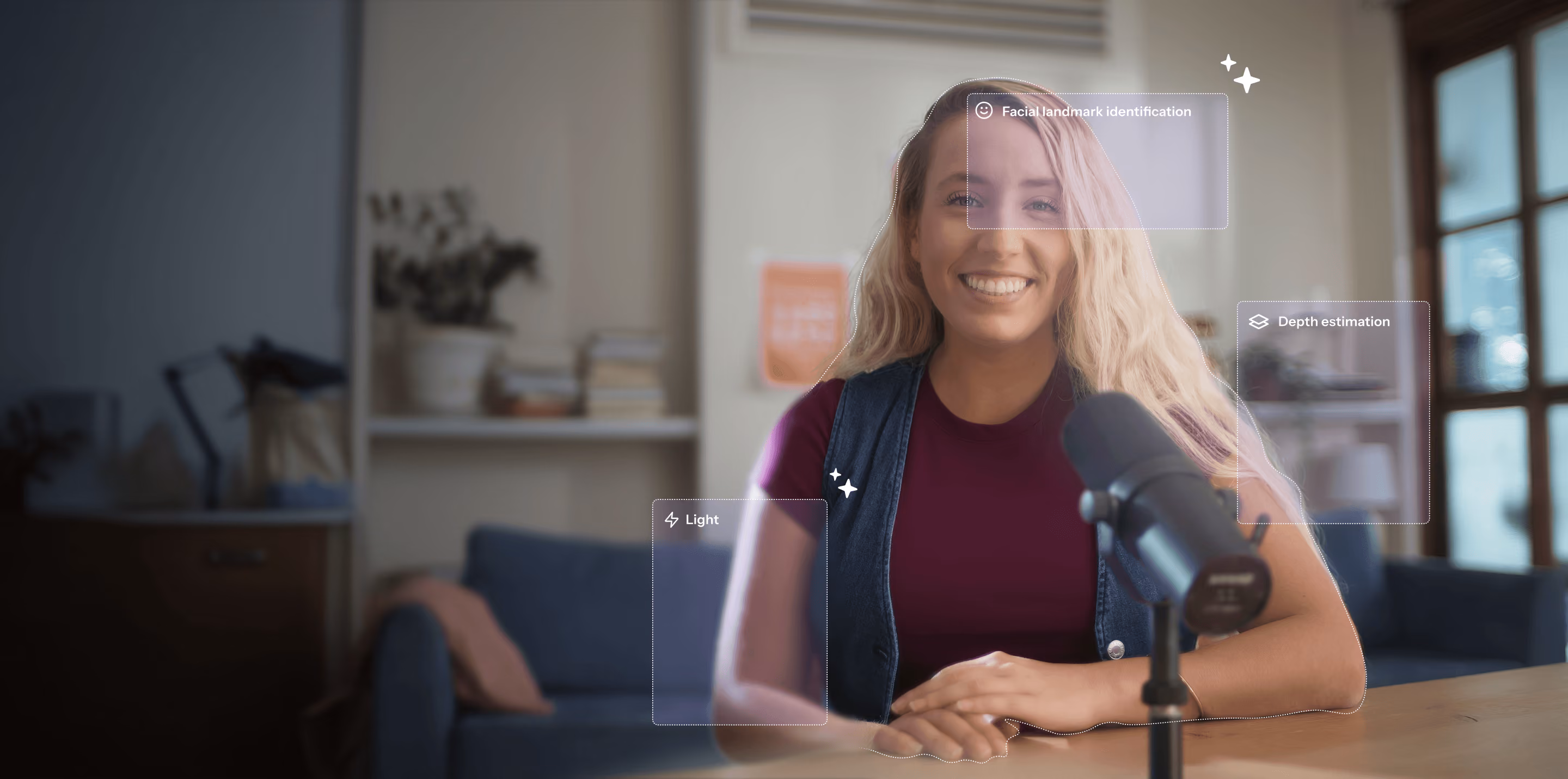 Woman sits at a table speaking into a microphone indoors.