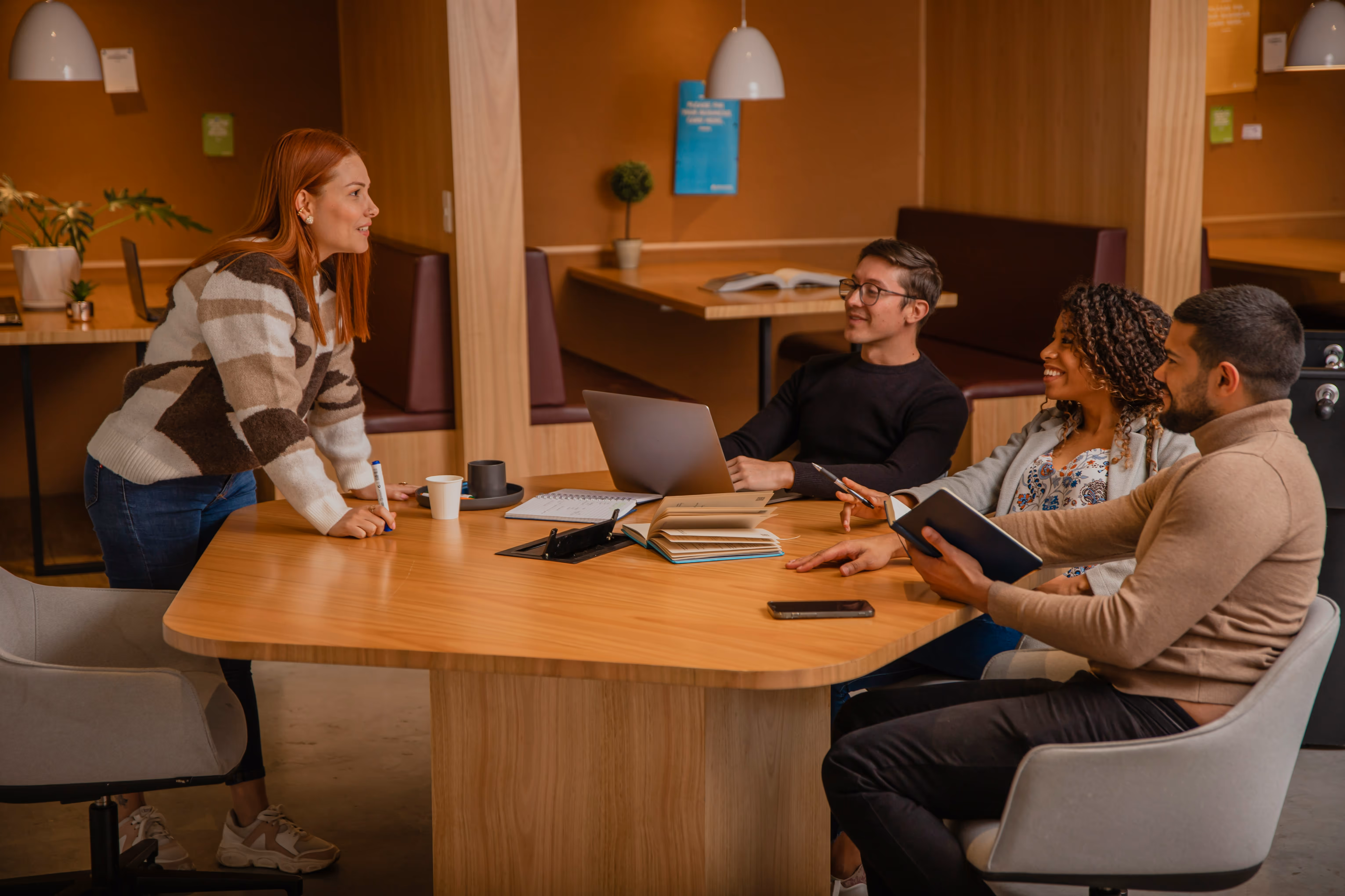 Four people working together on a desk in an office 
