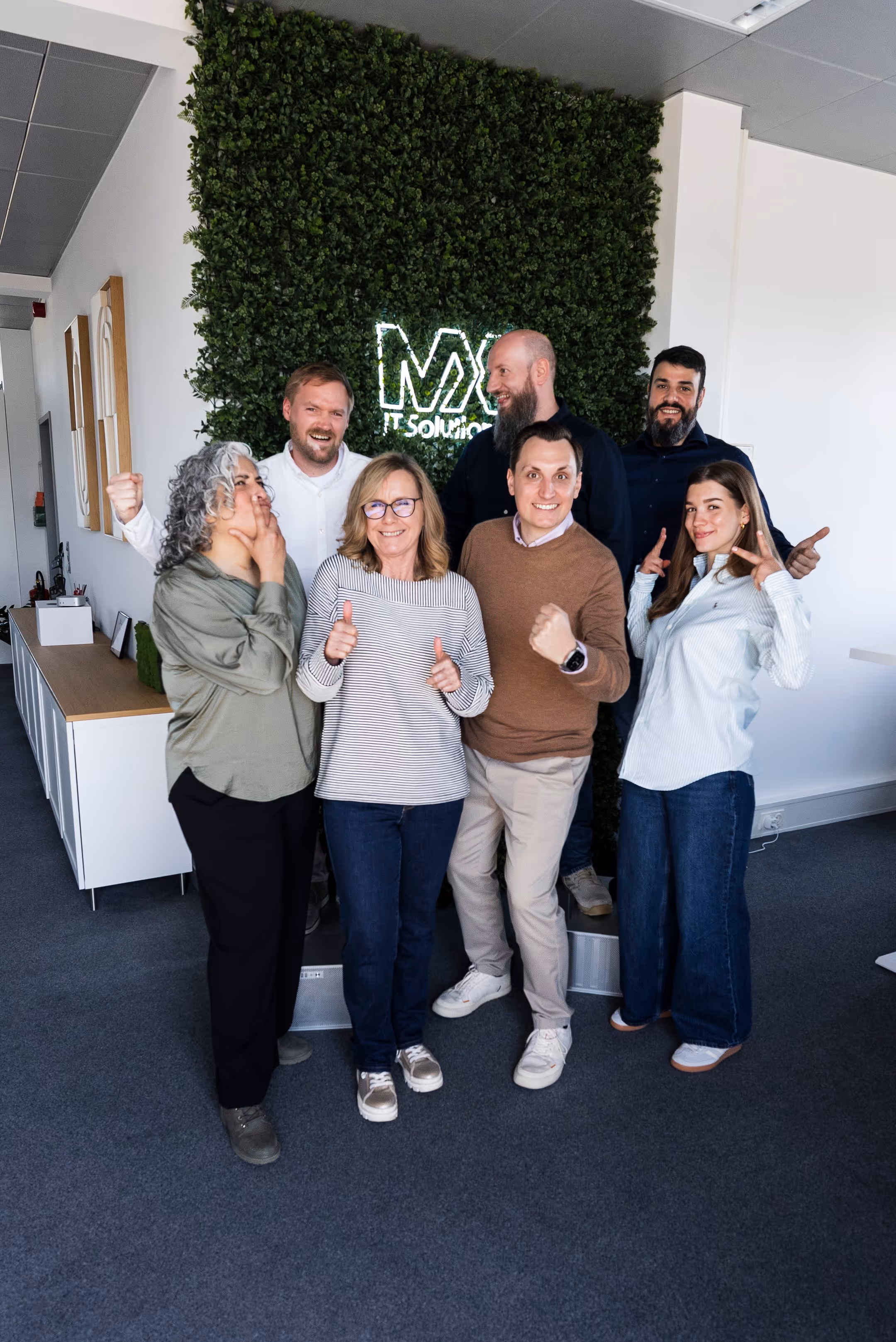 A group of people in front of a green wall