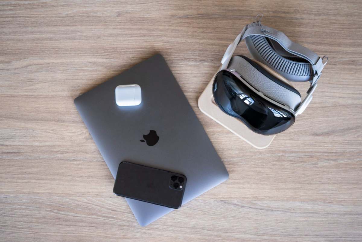 Apple-Geräte im Unternehmen: MacBook, iPhone, AirPods und Vision Pro auf einem Schreibtisch