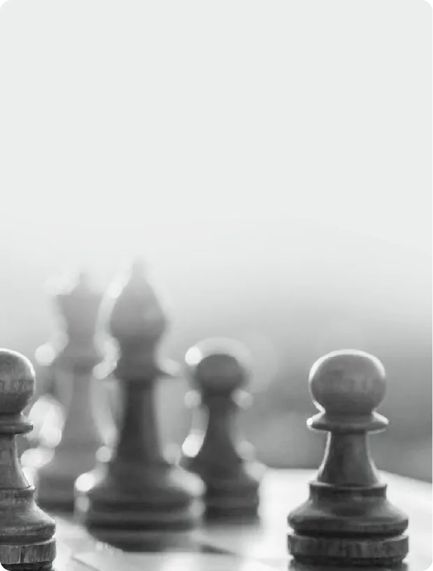 Black and white close-up of chess pawns and pieces on a chessboard with soft focus in the background.