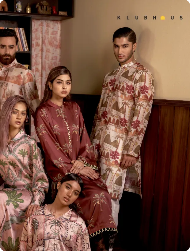 Group of four men and women wearing patterned traditional South Asian clothing posing indoors against a beige wall and wooden paneling.