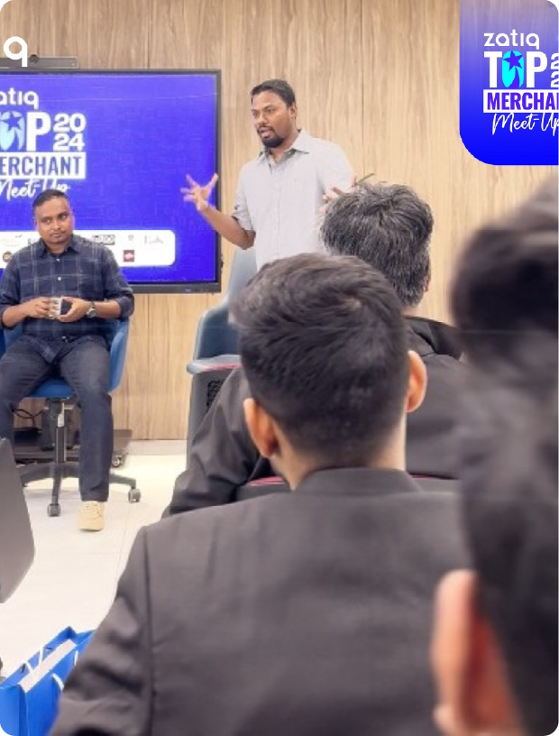 Man standing and speaking to an audience seated in chairs during the Zatiq Top Merchant Meet Up 2024 event.
