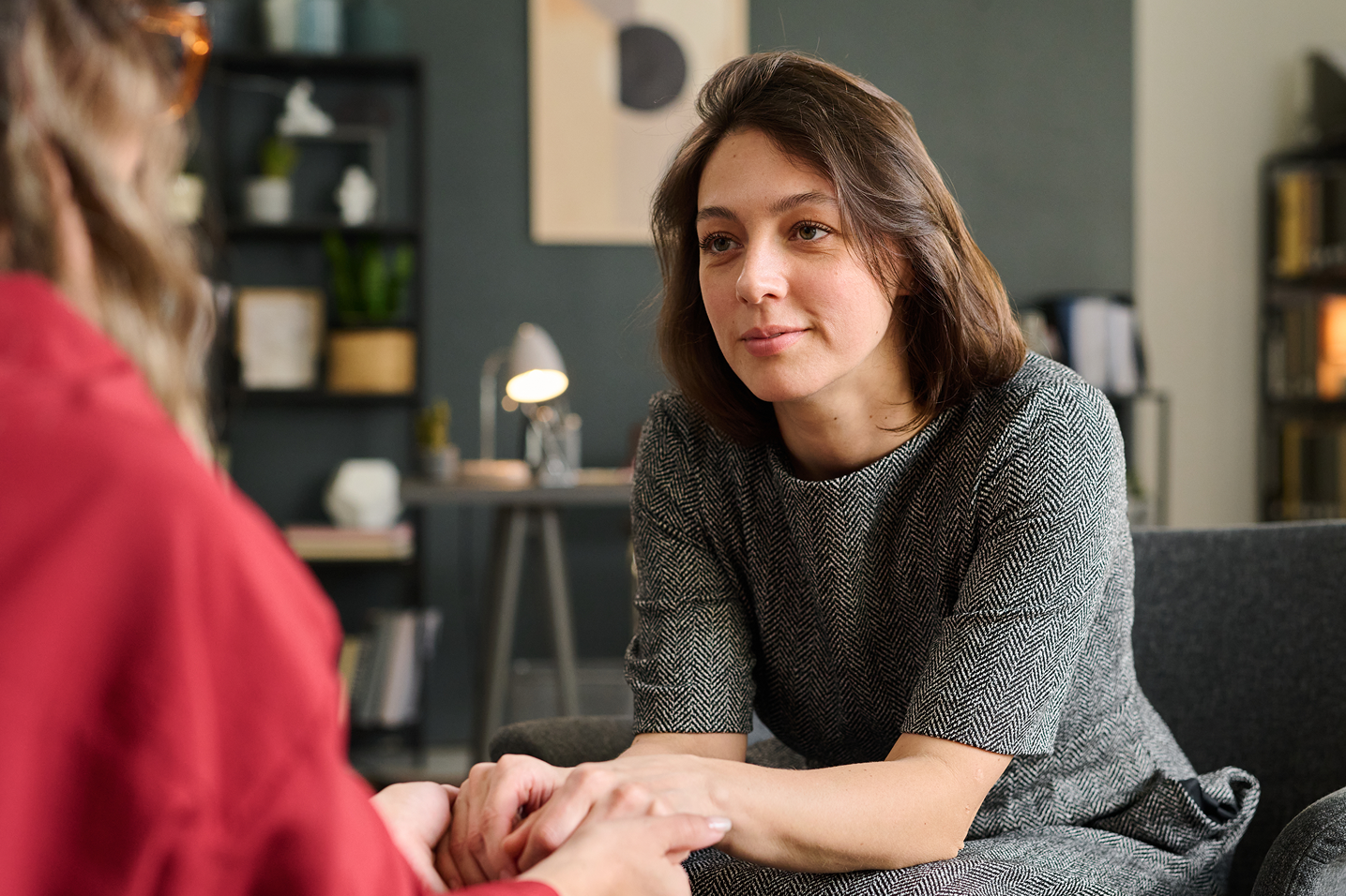A woman sitting on a couch talking to another woman.
