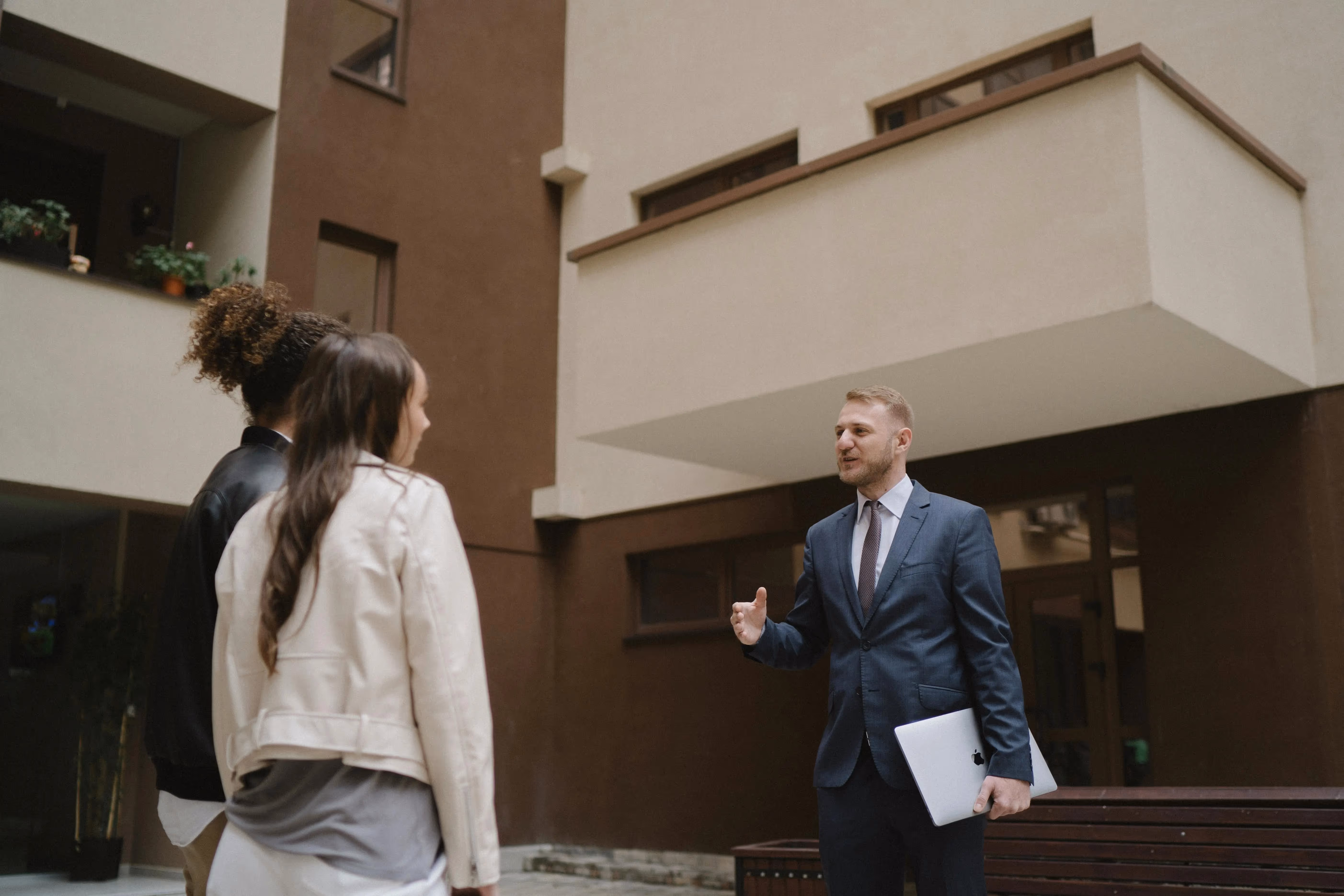 Professional property manager speaking with clients outside a residential building, representing Lynk Global’s admin support for real estate operations.