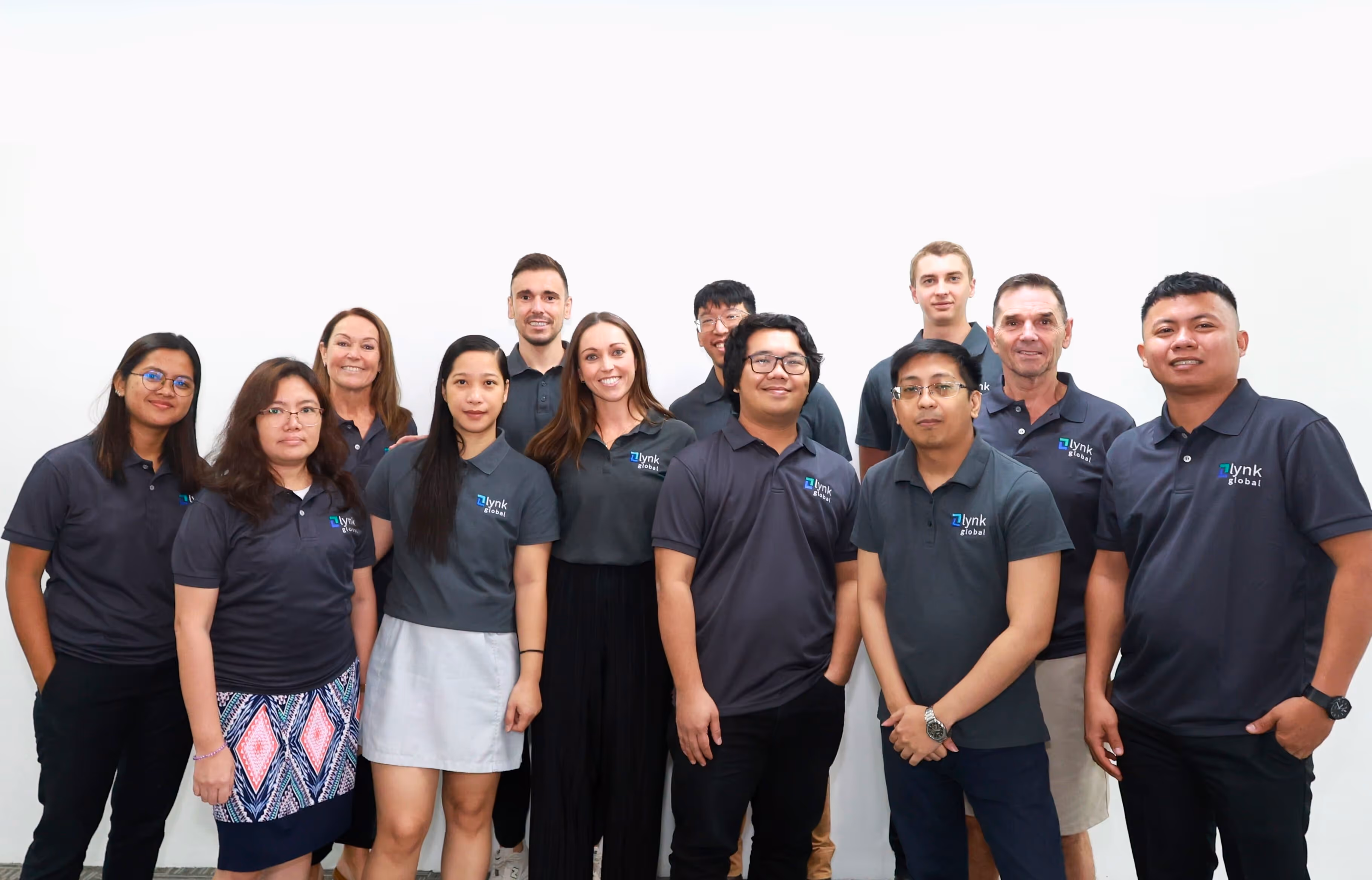 Lynk Global team standing together in office uniforms, representing a supportive and growth-focused workplace culture