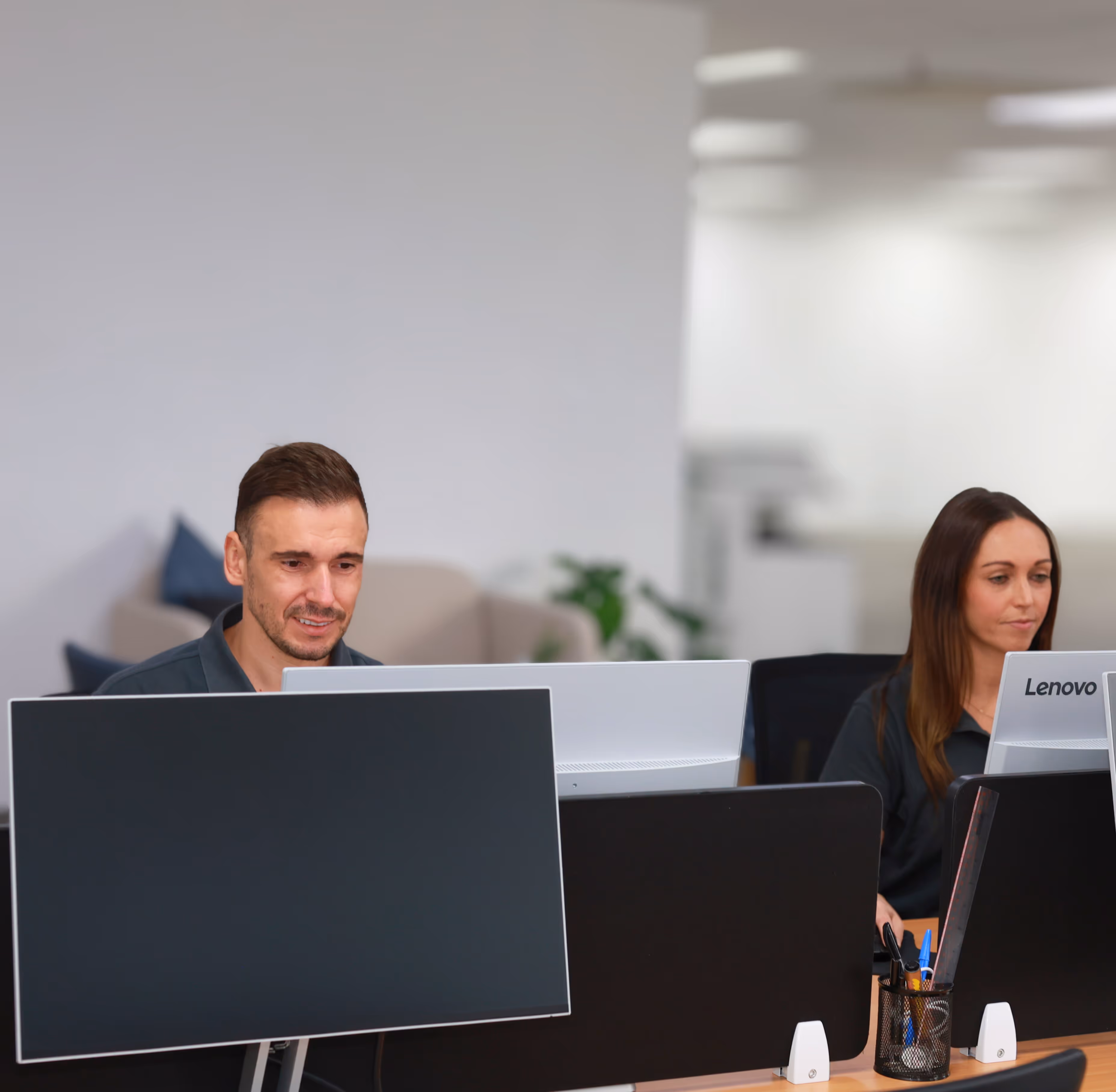 Daniel and Jessica working side by side in the Lynk Global office, with on-screen tags reading “Quietly Reliable” and “Trusted,” reflecting the company’s values.