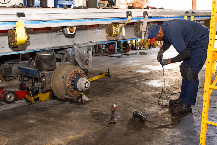 diesel mechanic replacing a tire on a flatbed trailer