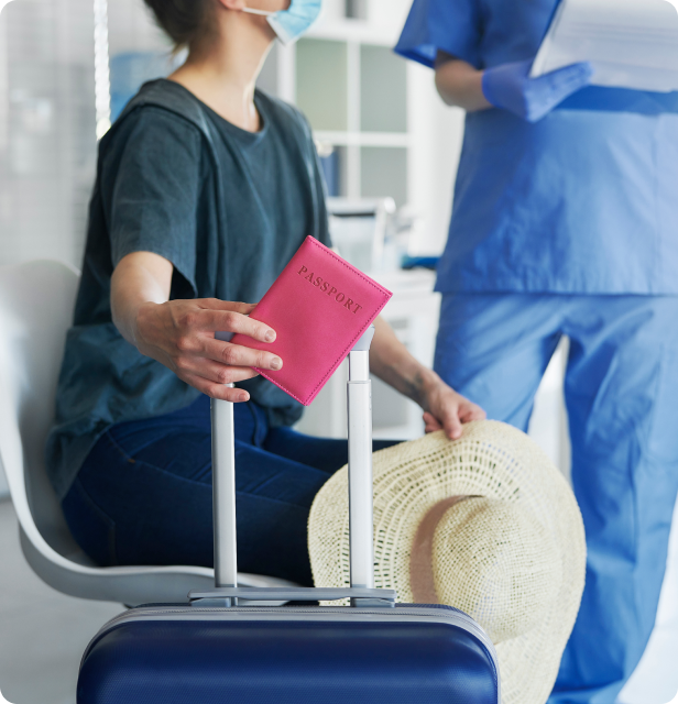 A person holding a passport and hat, sitting next to a suitcase, with a medical professional in the background.