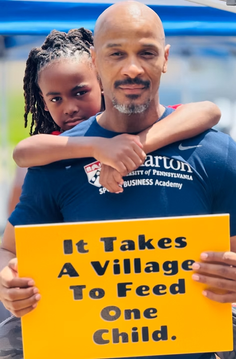 Volunteer serving food to children in Philadelphia through It Takes a Village to Feed One Child program