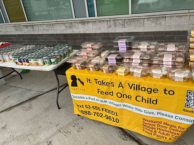 It Takes a Village to Feed One Child table displaying packed food for donation, nutritious meals for children and families in Philadelphia”