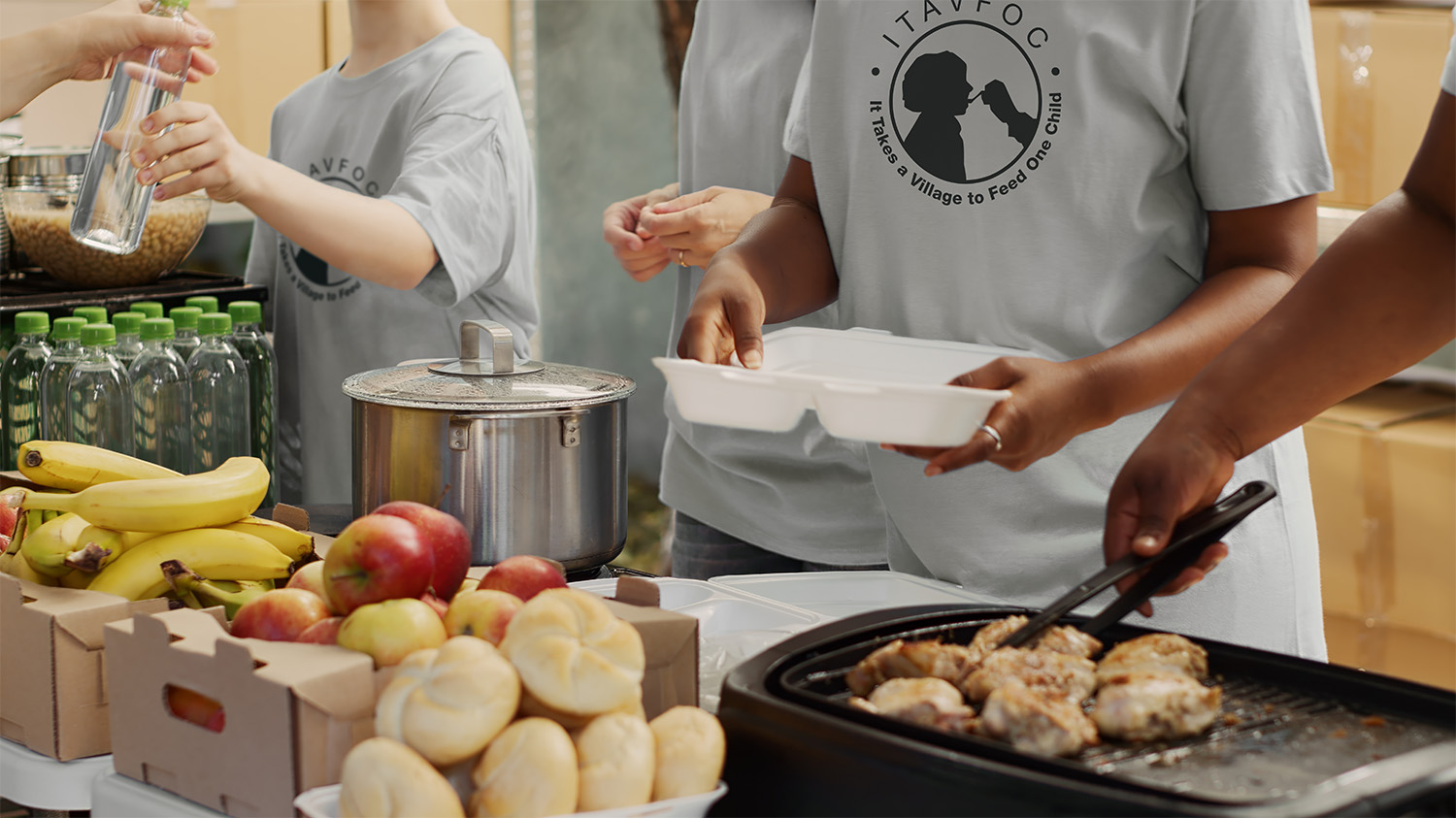 A group of diverse volunteers preparing food in trays, ready to serve people at risk part of every program held by It Takes A Village To Feed One Child nonprofit