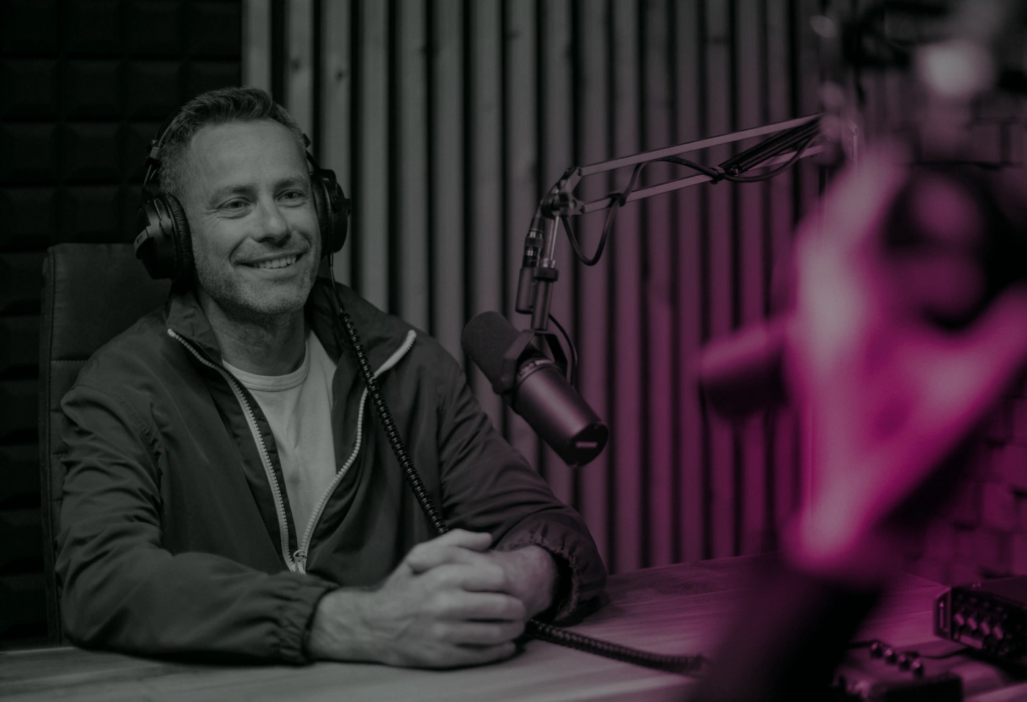 man sitting with headphones on and speaking into a mounted microphone