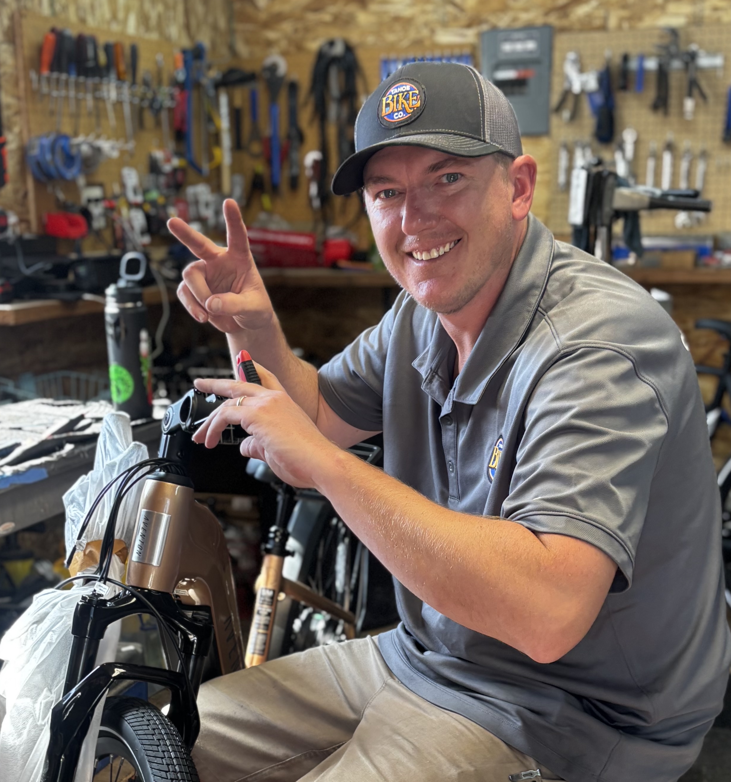 Nick, Lead Mechanic and Operations Manager, giving a peace sign while working on an e-bike in the Tahoe Bike Company shop