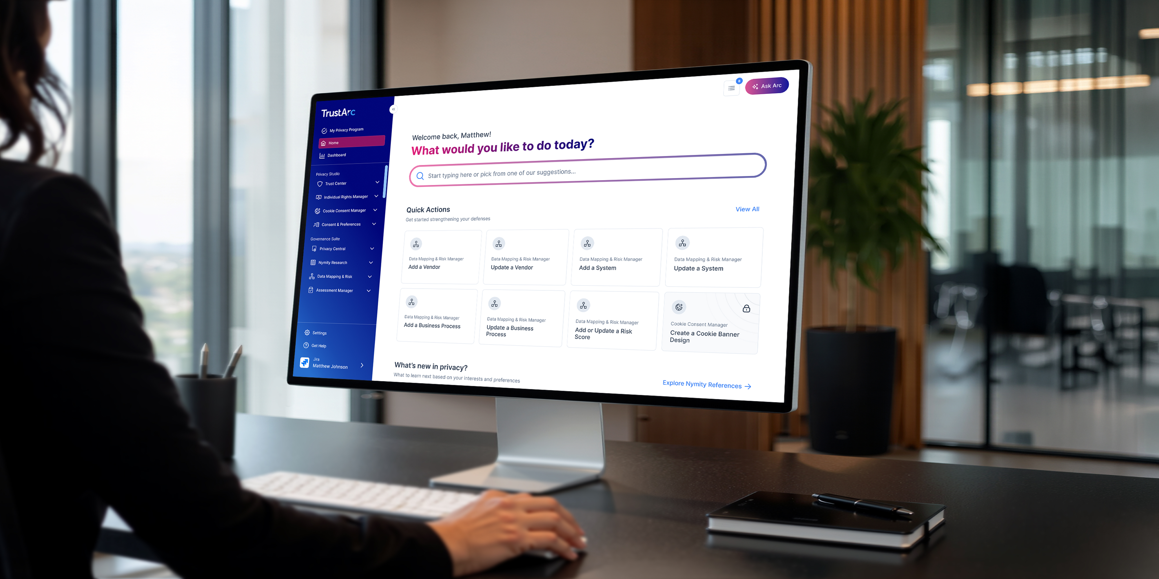 Person using a computer showing TrustArc dashboard with privacy program management options.