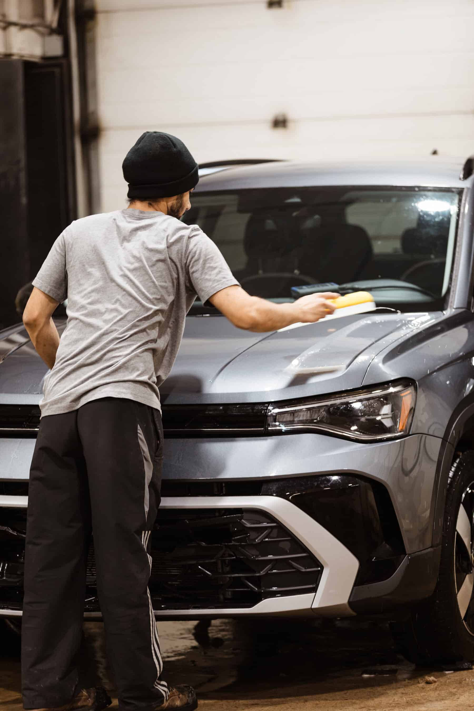 A man detailing a car in a garage.