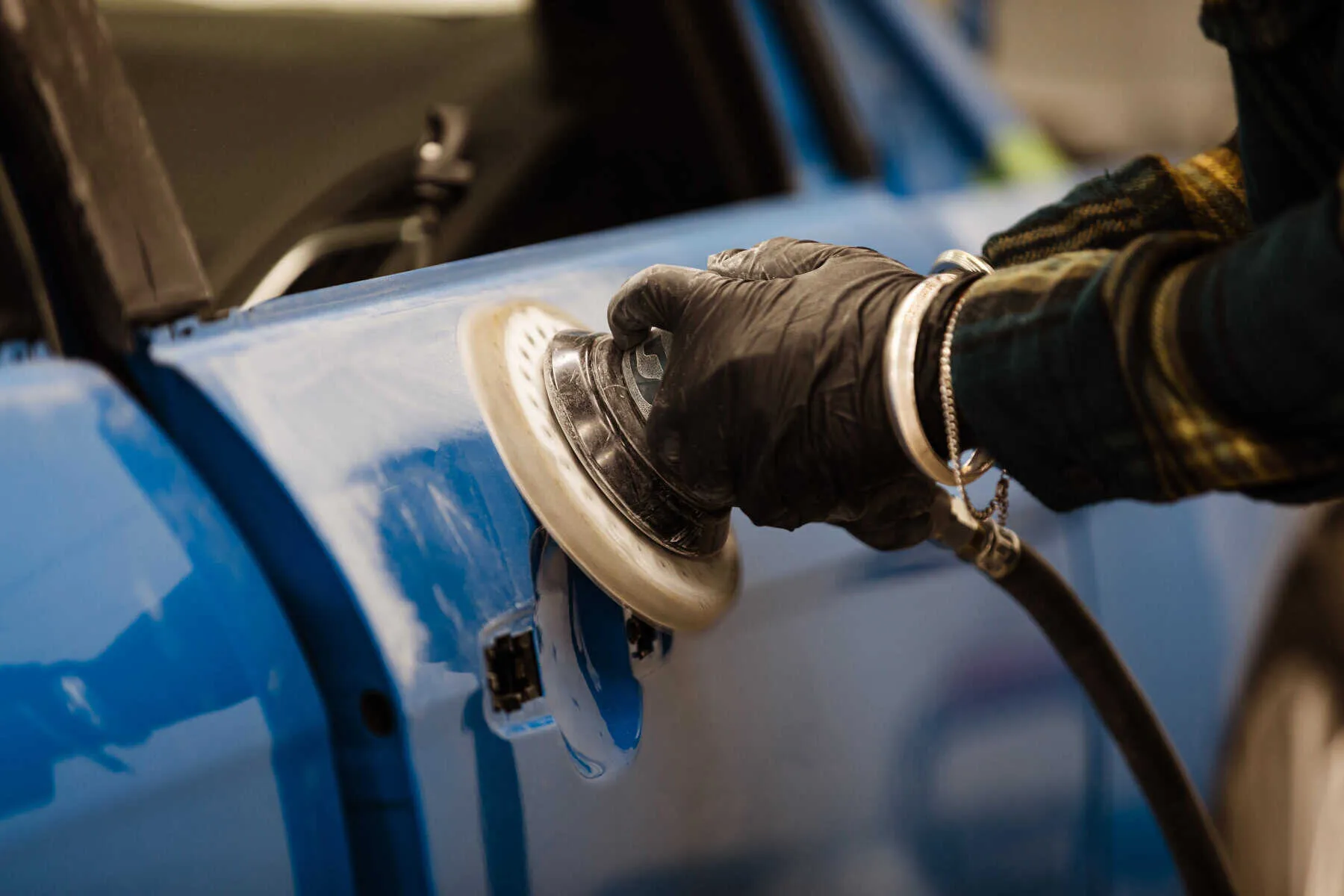 A person in gloves is waxing a car.