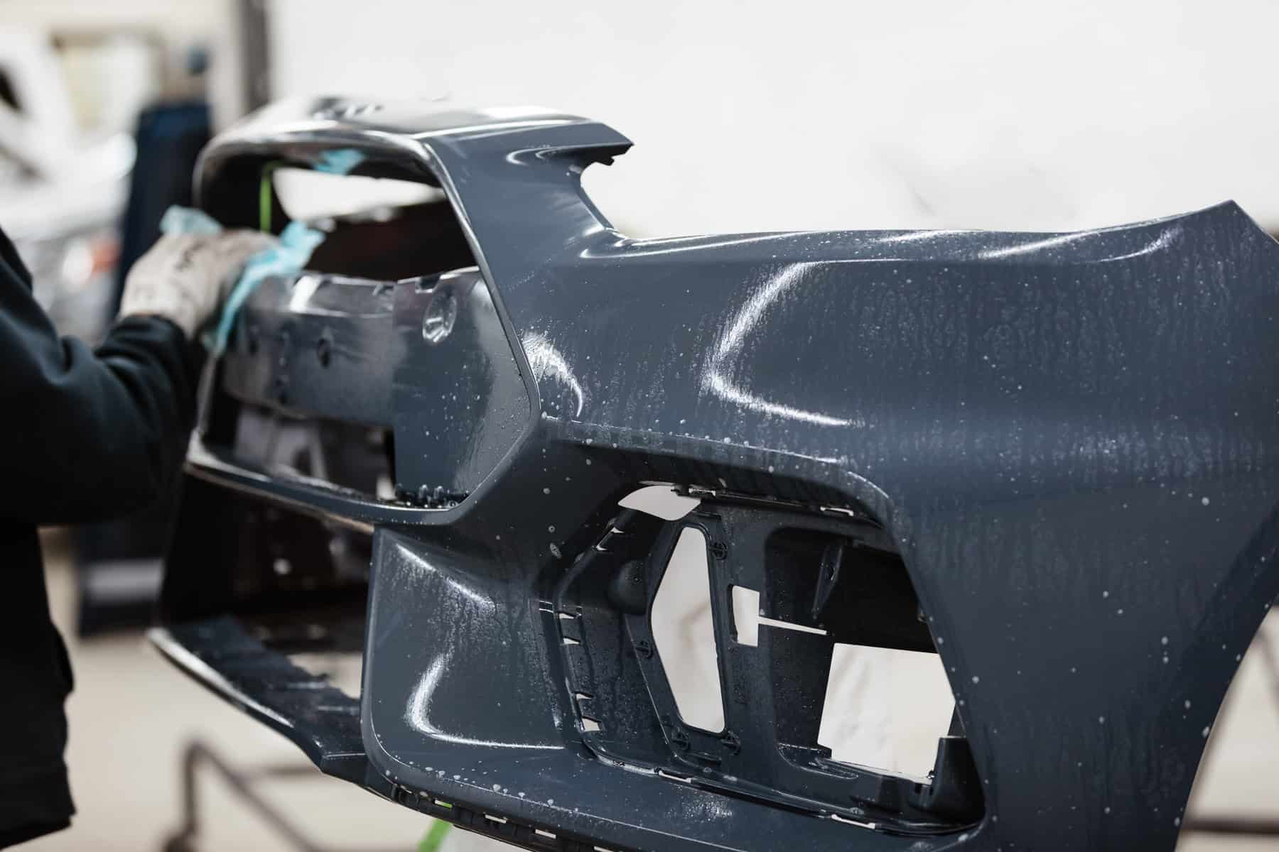 A person working on a car body in a garage.