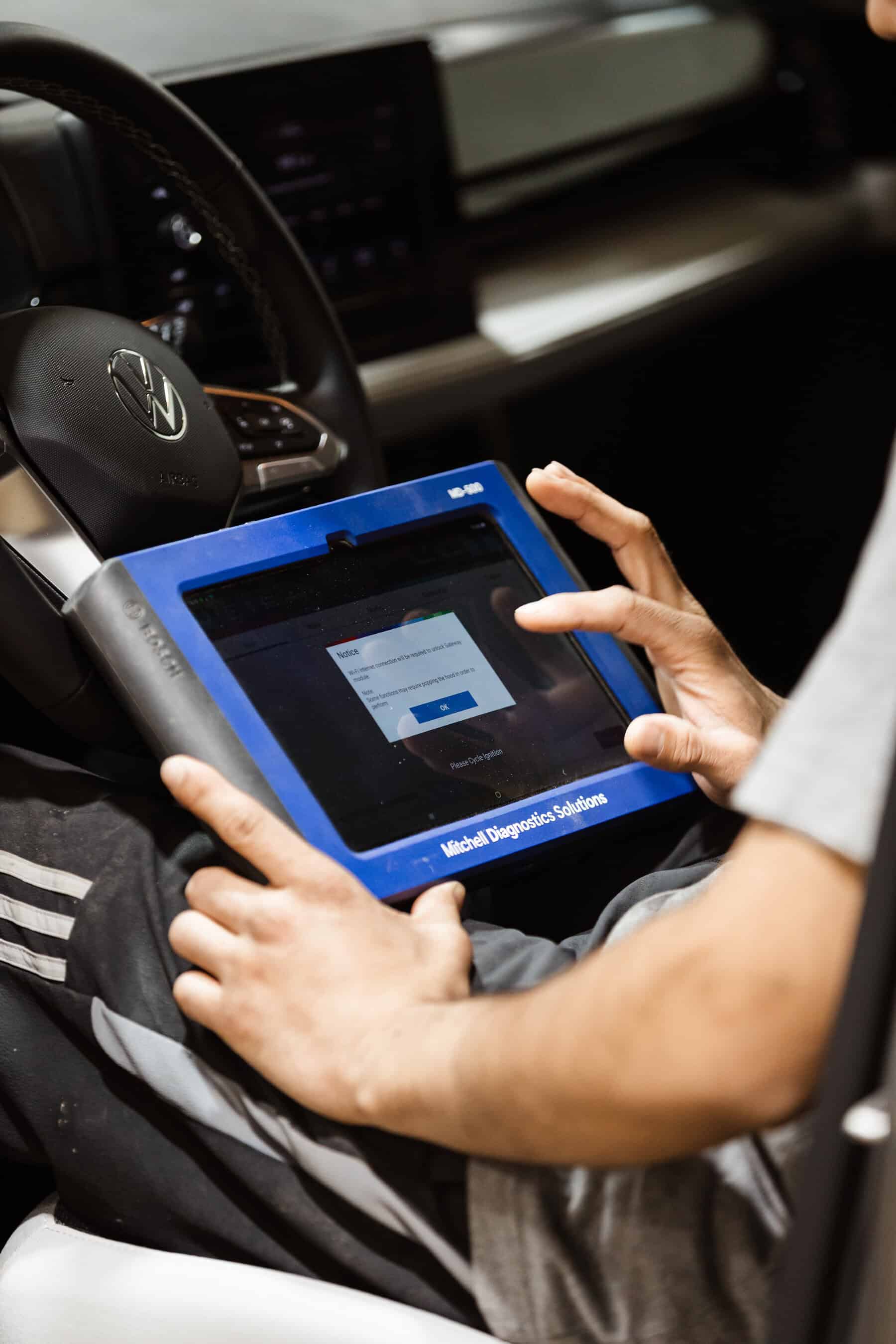 A man sitting in a car holding a tablet.