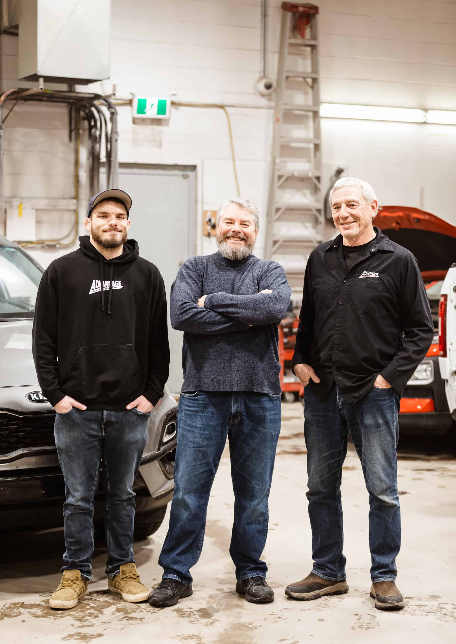 Three men standing next to each other in front of a car.
