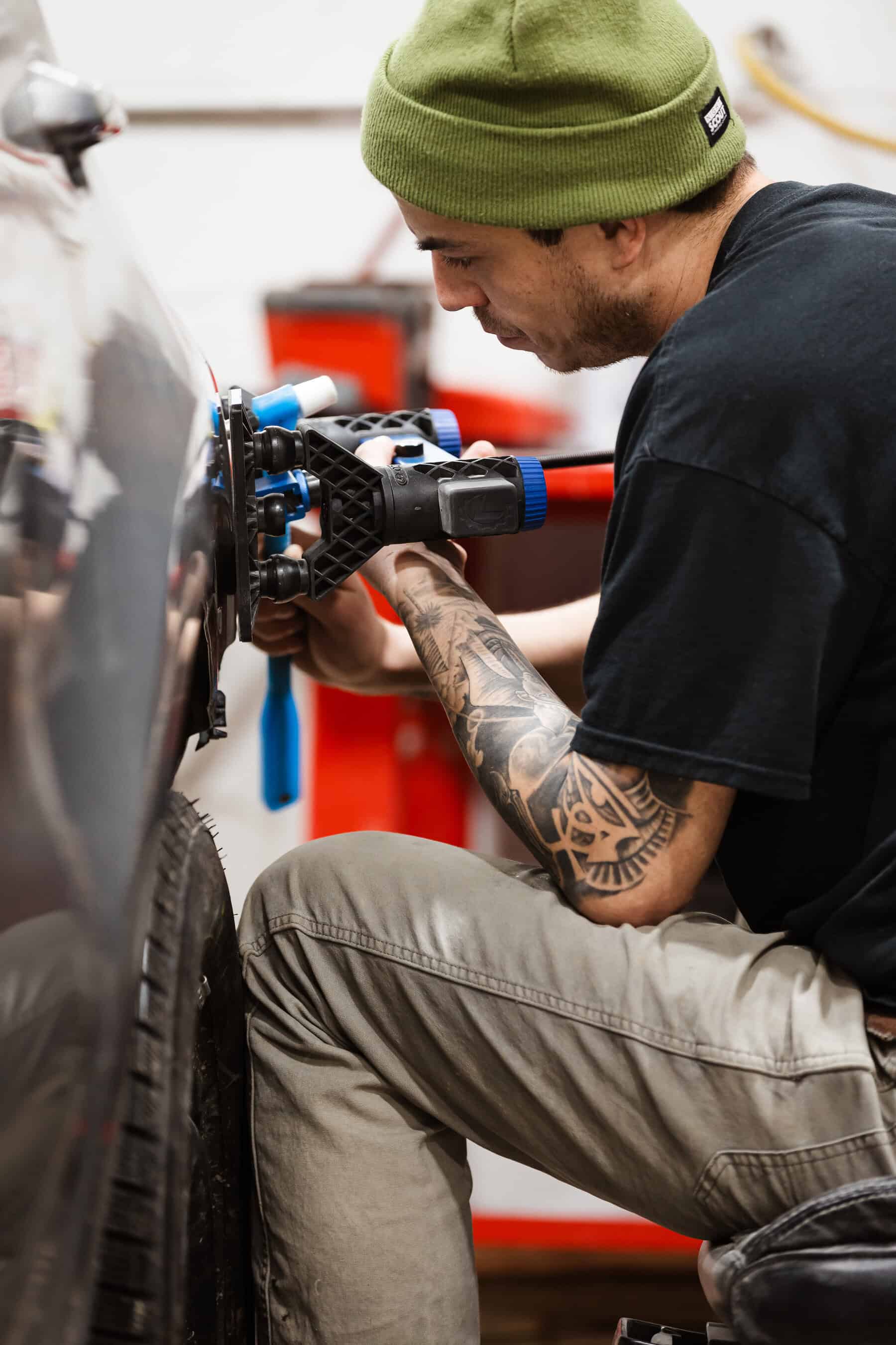 A man with a green hat working on a vehicle.