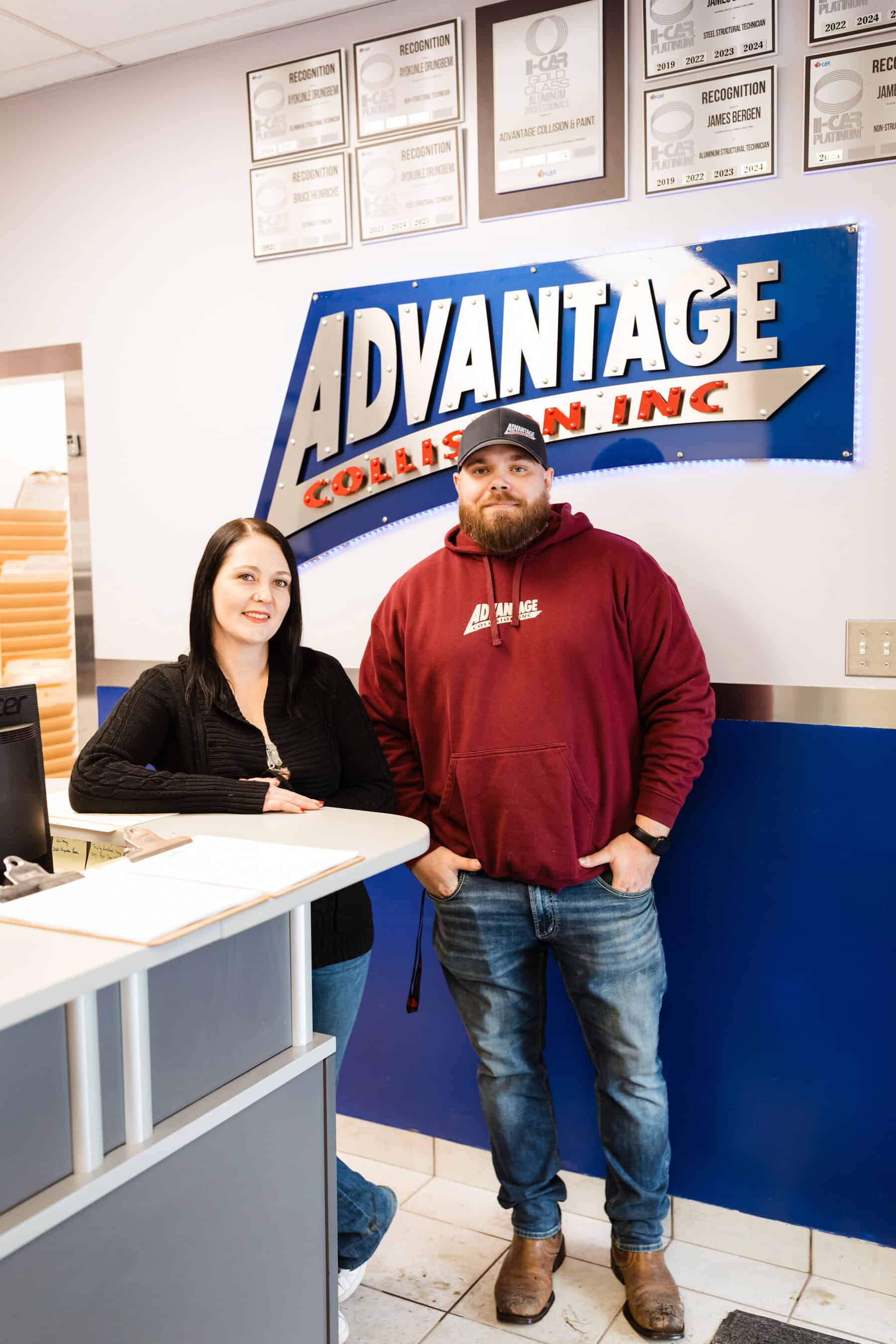 A man and a woman standing in front of a sign.
