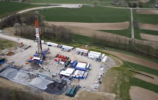 Aerial view of an oil drilling site with equipment in rural farmland
