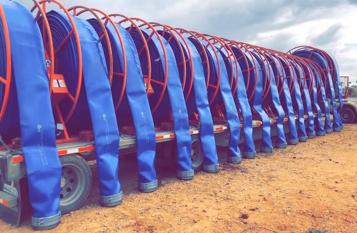Multiple blue industrial hoses with red frames lined up on trucks