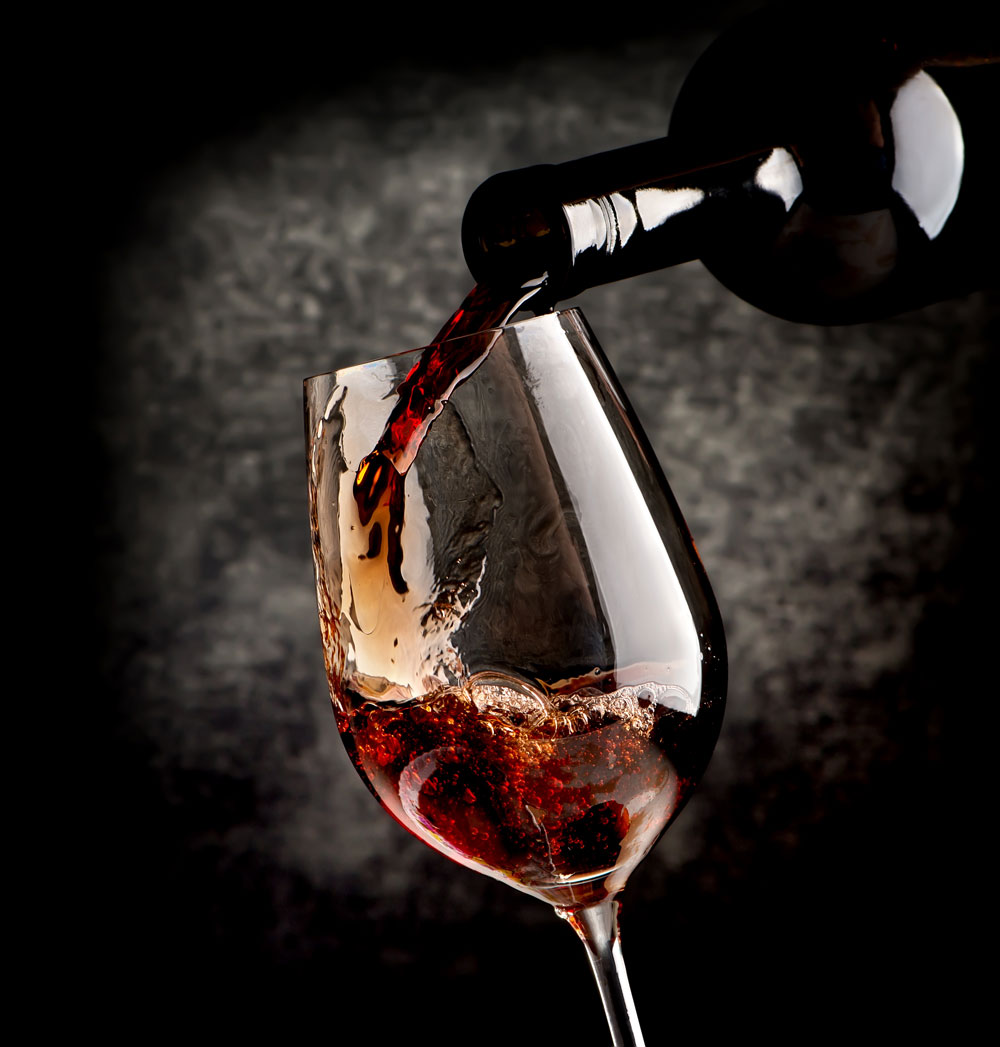 A glass of red wine with a black background.