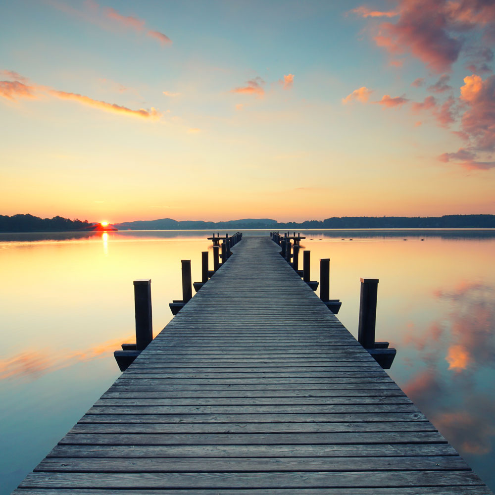 A pier with a wooden walkway and a sunset in the background.