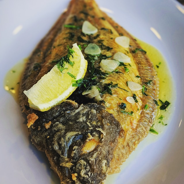 A fish with a lemon wedge on top.