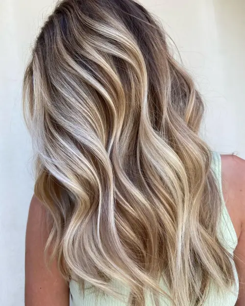 Blonde balayage with soft, sun-kissed highlights on wavy, shoulder-length hair, styled at Razberris Salon in Toms River, NJ.