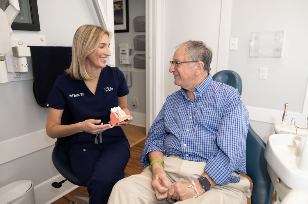Smiling patient at the dentist comparing porcelain and composite veneers with a dental professional.