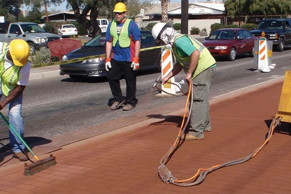 Applicators installing a patterned asphalt in between traffic lanes