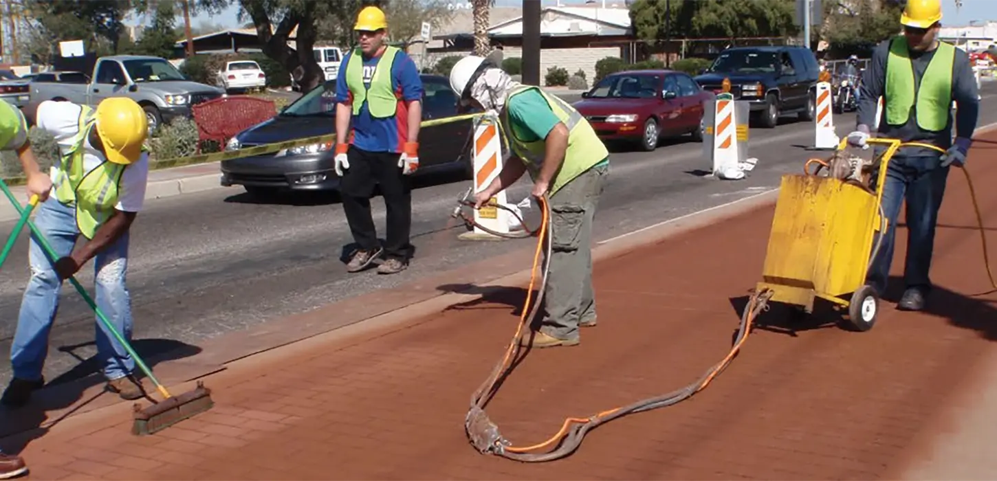 Applicators installing a patterned asphalt in between traffic lanes