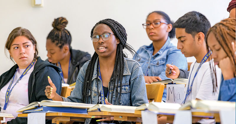 Student works at a computer and looks toward 3d printer.