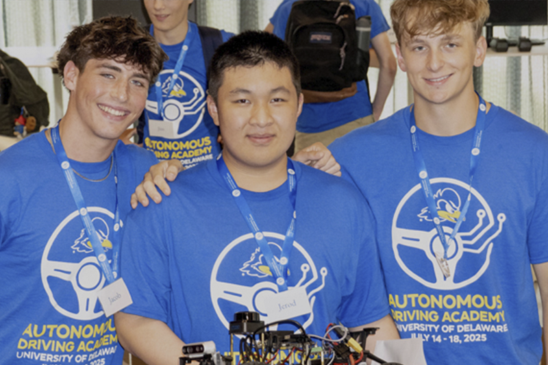 Student works at a computer and looks toward 3d printer.